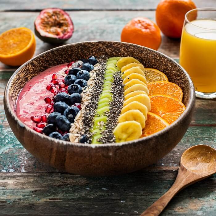 An inviting chilled smoothie bowl, topped with a variety of fresh fruits, granola, and seeds, ready to be enjoyed.