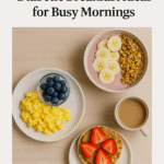Three diabetic-friendly breakfast dishes arranged on a light wooden table, including scrambled eggs with blueberries, a smoothie bowl topped with banana slices and granola, and a toasted English muffin with peanut butter and sliced strawberries, accompanied by a mug of coffee.
